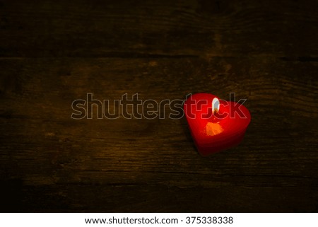 Candle in the form of heart on the wooden background