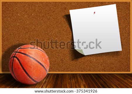 Rugged and seasoned basketball on a background cork board with copy space on pinned paper.