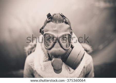 Environmental disaster.Woman breathing trough gas mask,health in danger.Concept of pollution,apocalypse.Polluted air,environmental problems.Riot with gas mask.Smog,poisonous particles,bio hazard Royalty-Free Stock Photo #375360064
