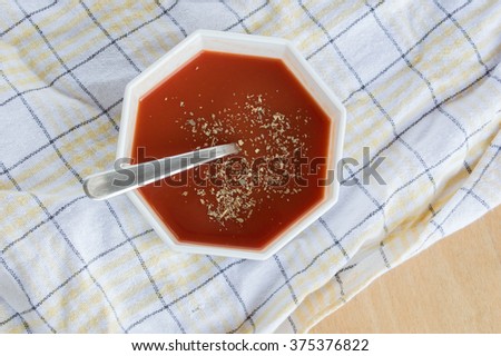 Top view of Tomato ketchup with oregano in white square bowl on plaid dishcloth