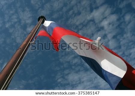 Russian state flag tricolor. Blue sky background.