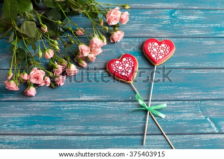 bouquet of mall pink roses lying on a white textured table next to two handmade baked hearts 