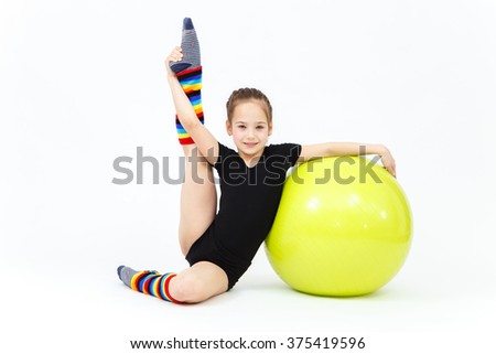 Flexible teen girl doing gymnastics exercises on fitness ball
