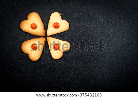 Heart shape homemade cookies on black stone background - love concept symbol - formed in four leaf clover
