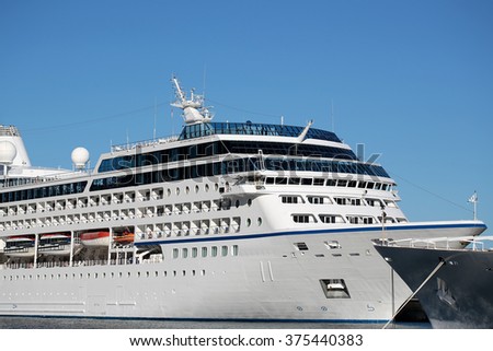 Photo of beautiful white modern ocean passenger liner at moorage in sea port on sunny summer day on seascape background, horizontal picture