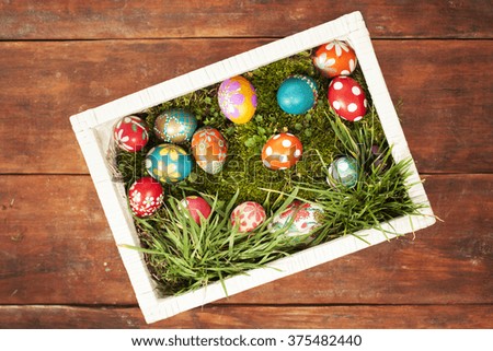 Colorful easter eggs on grass in white basket