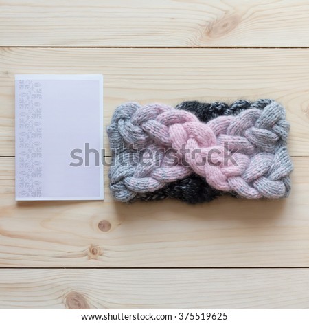 woolen headband on the head of the three colors associated manually on a wooden background next to the postcard