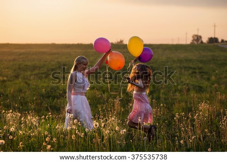 happy women and girl jumping with balloons outdoor