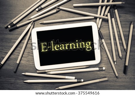 E-Learning topic on mobile tablet with many pencils on wood table