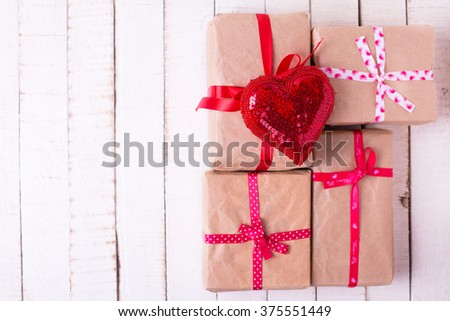 Festive gift boxes and red decorative heart  on white wooden background. Selective focus. Top view. Place for text.