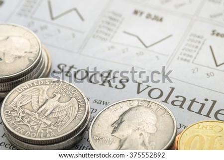 Newspaper open to stock market page showing word "Stocks Volatile" and coins. Concept of Investment. Royalty-Free Stock Photo #375552892
