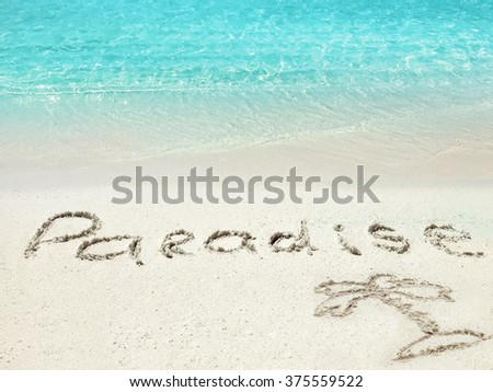 Inscription "Paradise" in the sand on a tropical island,  Maldives.