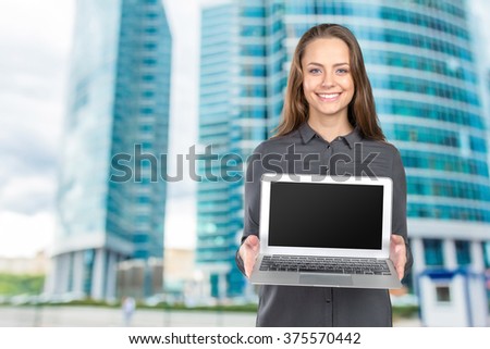 Portrait of a happy cute woman showing blank laptop screen 