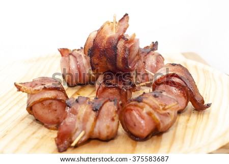 Deep fried sausages rolled in bacon over wood