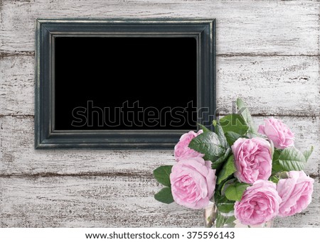 Roses and photo frame on background of shabby wooden planks in rustic style