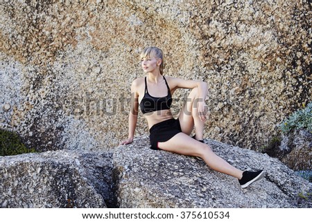 Beautiful woman athlete sitting on rock