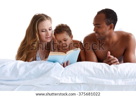 Mother and father reading with her son on bed. Concept of cheerful American family
