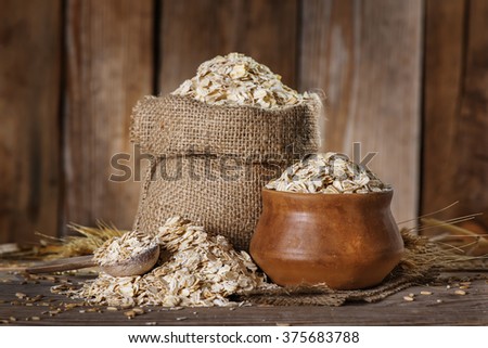 Oat,  flakes in a bag and a clay bowl, spoon on the old wooden background close-up
