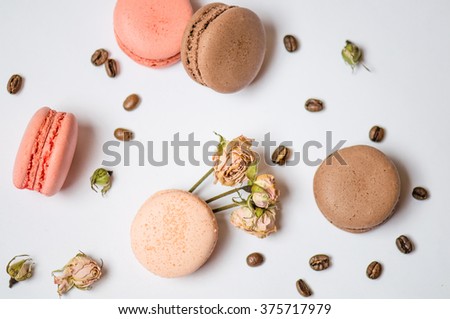 Macaroons almond cakes - best delicacy for children and adults. French dessert, coffee beans and dry roses on a white table close-up.

 Royalty-Free Stock Photo #375717979