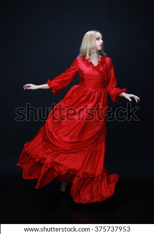 full length portrait of a beautiful blonde woman wearing a historical red silk, victorian era ball gown.
black studio background, not isolated.
