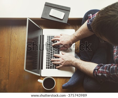 Man on wooden floor using laptop computer high angle view