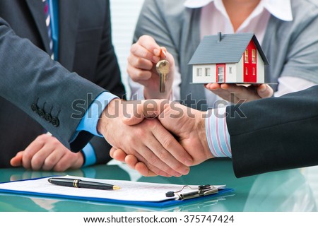 Estate agent shaking hands with customer after contract signature Royalty-Free Stock Photo #375747424