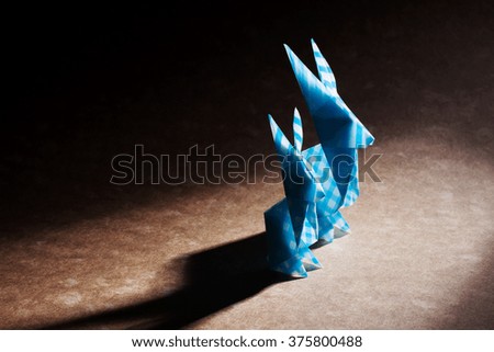 Two origami rabbits together over craft background