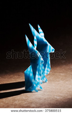 Two origami rabbits together over craft background
