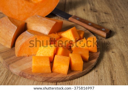 Orange pumpkin cut on a wooden board.