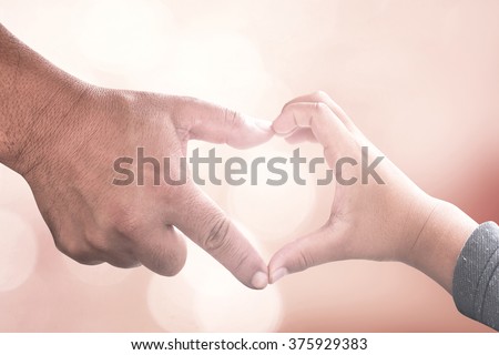 Family day concept: Father and son hands make heart shape over blurred pink nature background Royalty-Free Stock Photo #375929383
