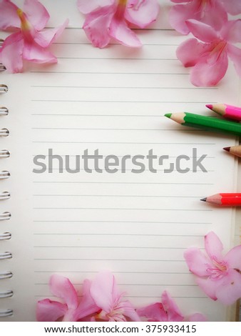 background of open notebook with pink flower included pencils 