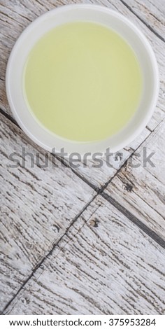 Grape seed oil in white bowl over wooden background