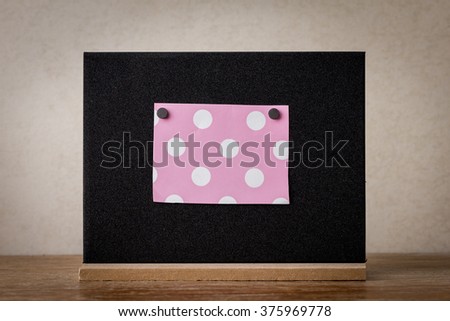 Pink polka dots paper on blackboard in the room.