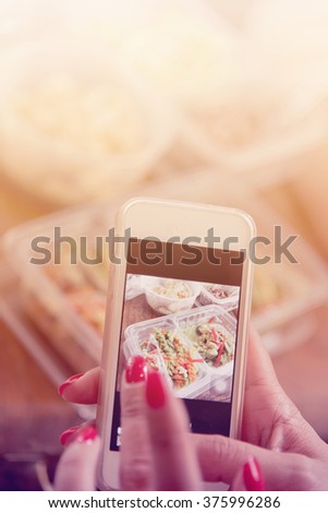 Woman hand with red nails taking photo of  food with smart phone