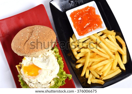 Burger with black pepper and French fries on the white table 