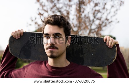 Handsome Man holding his skate under the Sun