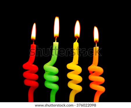 Burning colorful birthday candles on black background