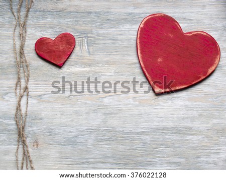 Two wood valentine's hearts lie on rustic wood texture background with twine.