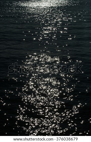 Closeup beautiful magic magnificent natural bright light of moon glade shines on dark sea water with waves seaways at night offing marine view sea scene, vertical picture