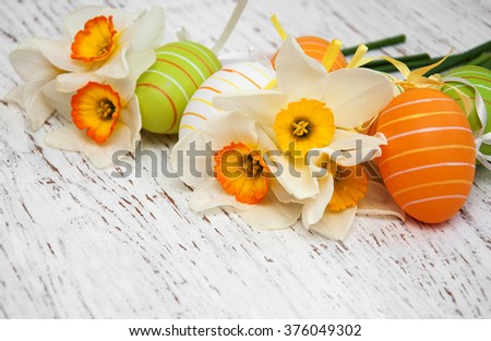 Easter eggs and daffodils flowers on a old wooden background
