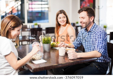 Group of three friends eating some healthy food at a restaurant and having a good time