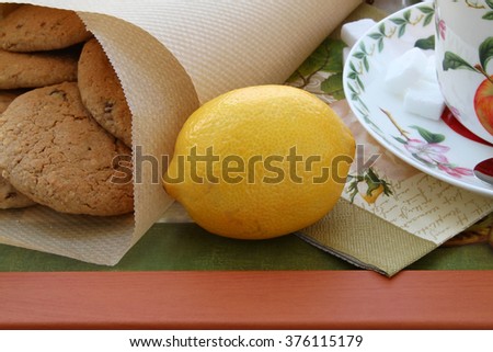 Yellow lemon for tea drinking and oatmeal cookies on a tray
