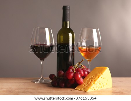 Refined still life of wine, cheese and grapes on wicker tray on wooden table