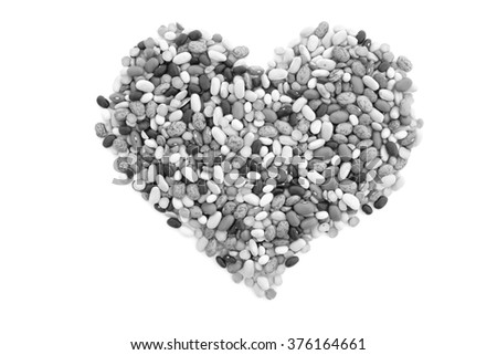 Mixed dried beans in a heart shape, isolated on a white background - monochrome processing