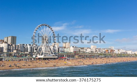 Brighton view of seaside from the pier. Panoramic shot with the famous ferris wheel, the stones beach with unrecognizable persons on a sunny summer day. Royalty-Free Stock Photo #376175275