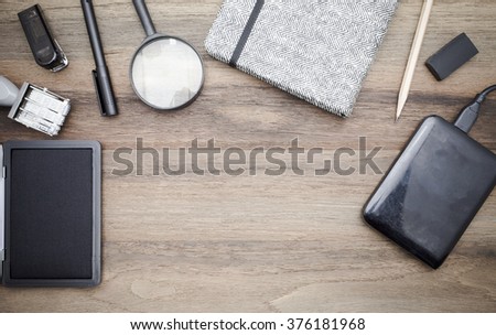 Workstation concept top view : Stapler,pen,magnifier,book,pencil,harddisk,keyboard on wooden background.In film tone
