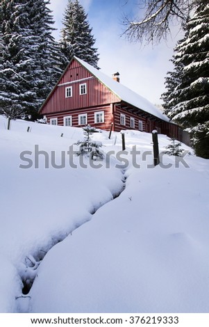 Red wooden cabin in a frosty snowy country in sunny winter day