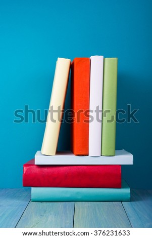 Stack of colorful books, grungy blue background, free copy space. Vintage old hardback books on wooden shelf, deck table, no labels, blank spine. Back to school,  instagram filter. 