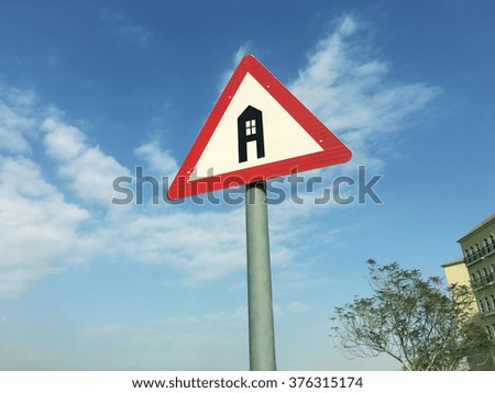 'Home' symbol on traffic sign against residential building background. 'Dream home ahead' concept.