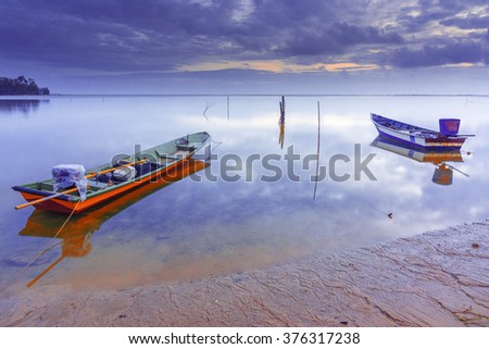 Boat on lake with a reflection in the water at sunset taken with Slow Shutter. Motion Blur, Soft Focus due to Slow Shutter Speed. Copy Space Area.